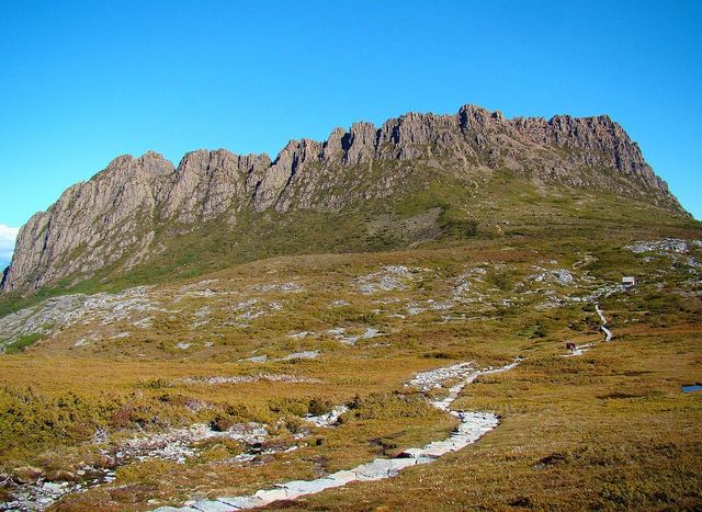 The Overland Track winding past Cradle Mountain on a midsummer day. The cabin seen in the right centre is Kitchen Hut, only for emergency use.